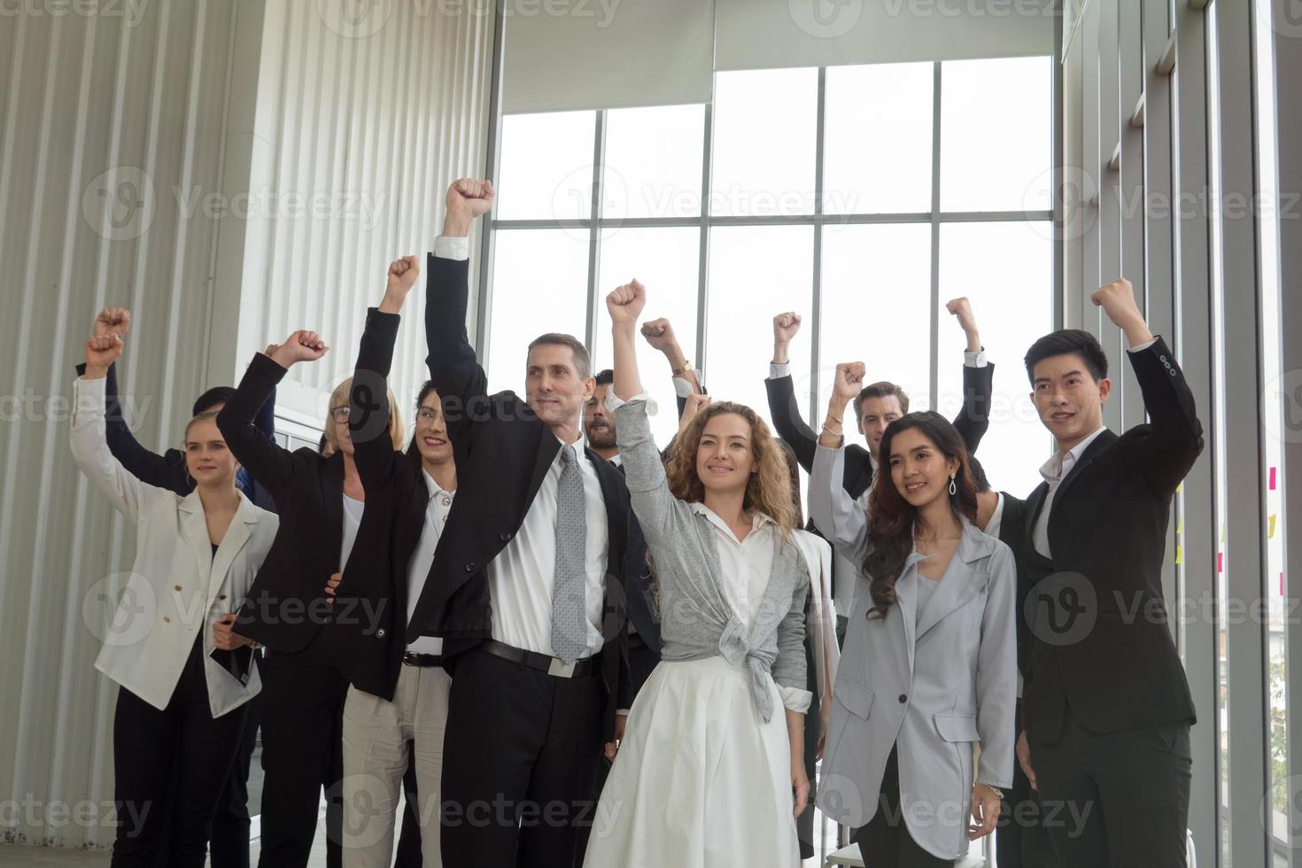 Successful business people standing together widen out showing strong relationship of worker community. A team of businessman and businesswoman expressing a strong group teamwork at the modern office. photo