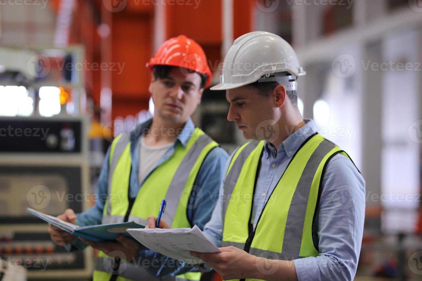 ingeniero industrial masculino con casco de seguridad mientras está de pie en una fábrica industrial pesada. el mantenimiento que busca trabajar en maquinaria industrial y verificar la configuración del sistema de seguridad en fábrica. foto