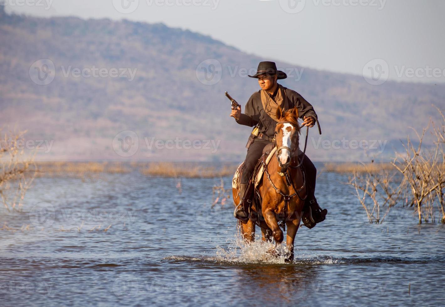 Cowboy on horseback against a beautiful sunset, cowboy and horse at first light, mountain, river and lifestyle with natural light background photo