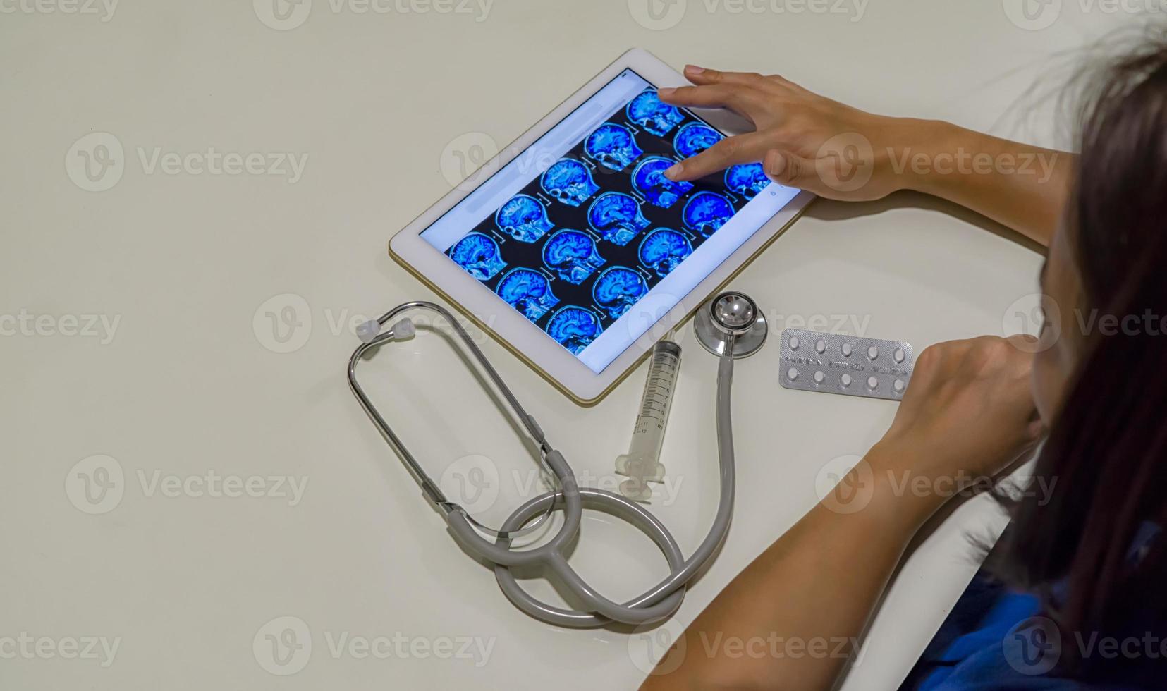 Doctor looking on radiological brain x-ray scan image on tablet for medical diagnosis photo