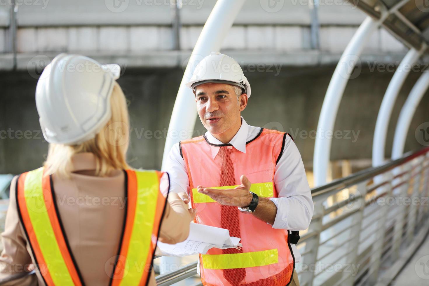 Contractor and architect looking at plan and talking about working on big project. Building in construction process interior. photo