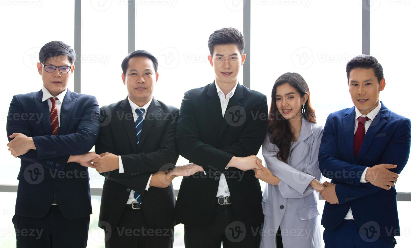 Successful business people standing together widen out showing strong relationship of worker community. A team of businessman and businesswoman expressing a strong group teamwork at the modern office. photo