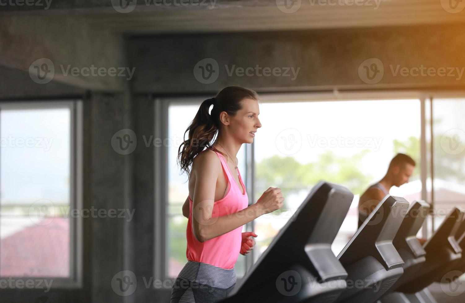 young woman running on treadmill at gym. photo