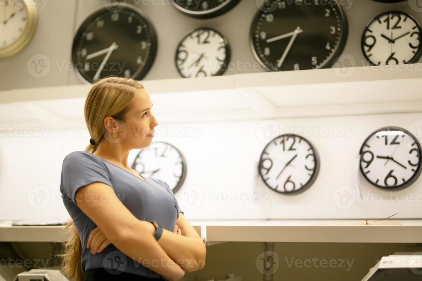 portrait of women looking away while standing against clocks on wall photo
