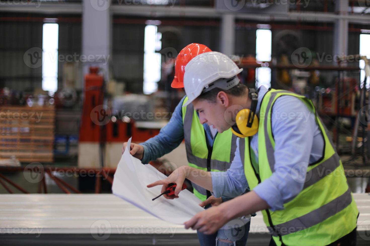 ingeniero industrial masculino con casco de seguridad mientras está de pie en una fábrica industrial pesada. el mantenimiento que busca trabajar en maquinaria industrial y verificar la configuración del sistema de seguridad en fábrica. foto