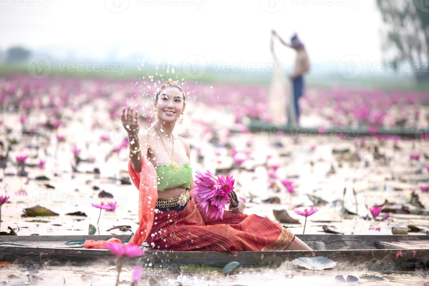 Young Asian women in Traditional dress in the boat and pink lotus flowers in the pond.Beautiful girls in traditional costume.Thai girl in retro Thai dress, Thai girl in traditional dress costume photo