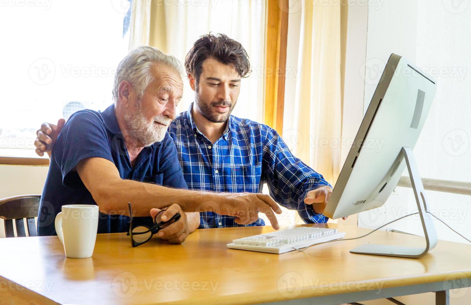 adult man teaching elderly man to using computer at home. photo