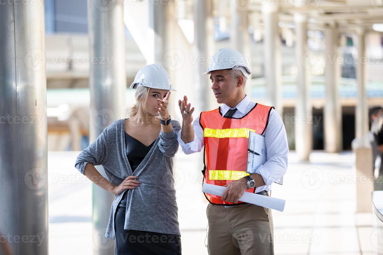 Contractor and architect looking at plan and talking about working on big project. Building in construction process interior. photo