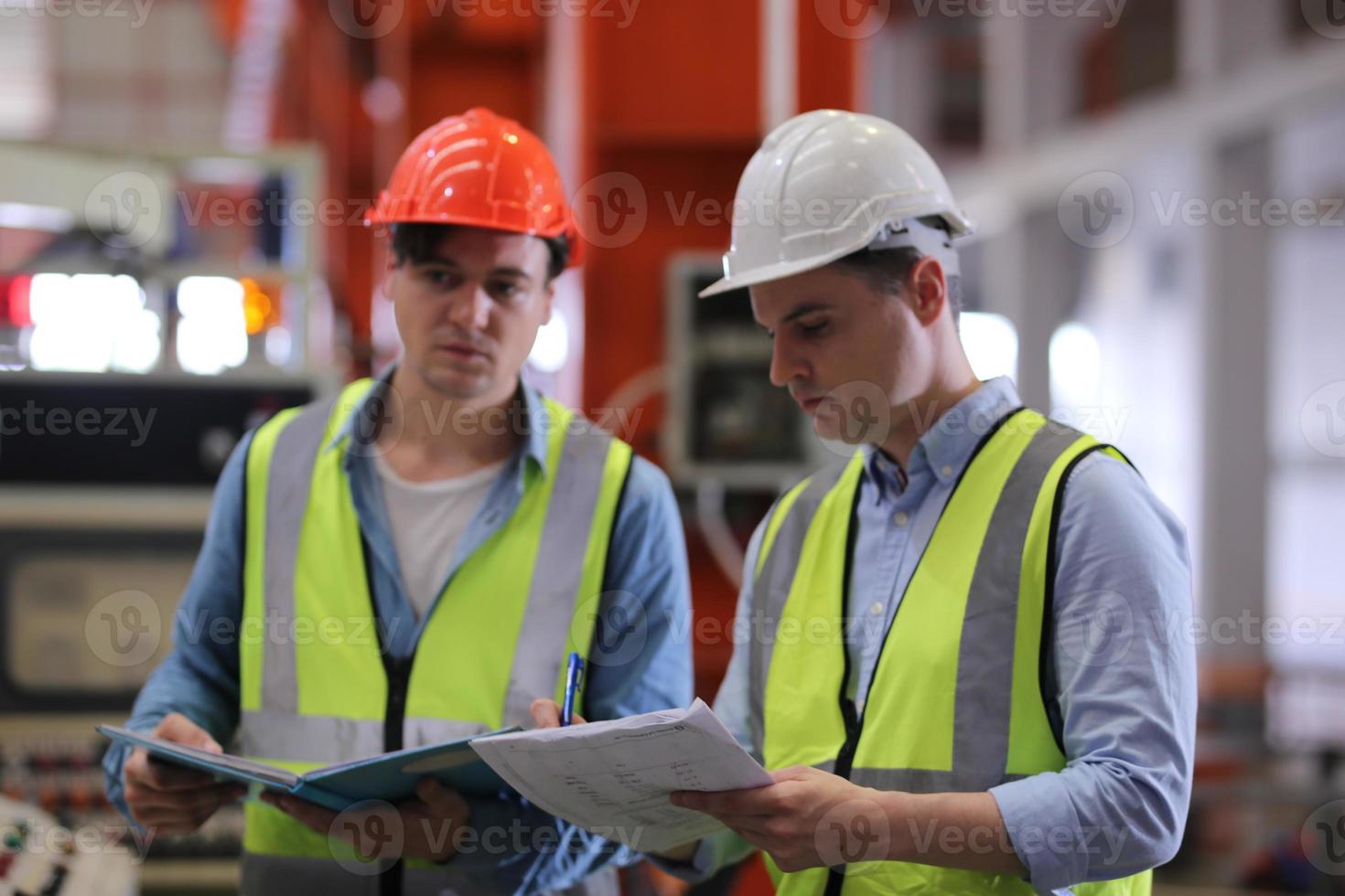 Men industrial engineer wearing a safety helmet while standing in a heavy industrial factory. The Maintenance looking of working at industrial machinery and check security system setup in factory. photo