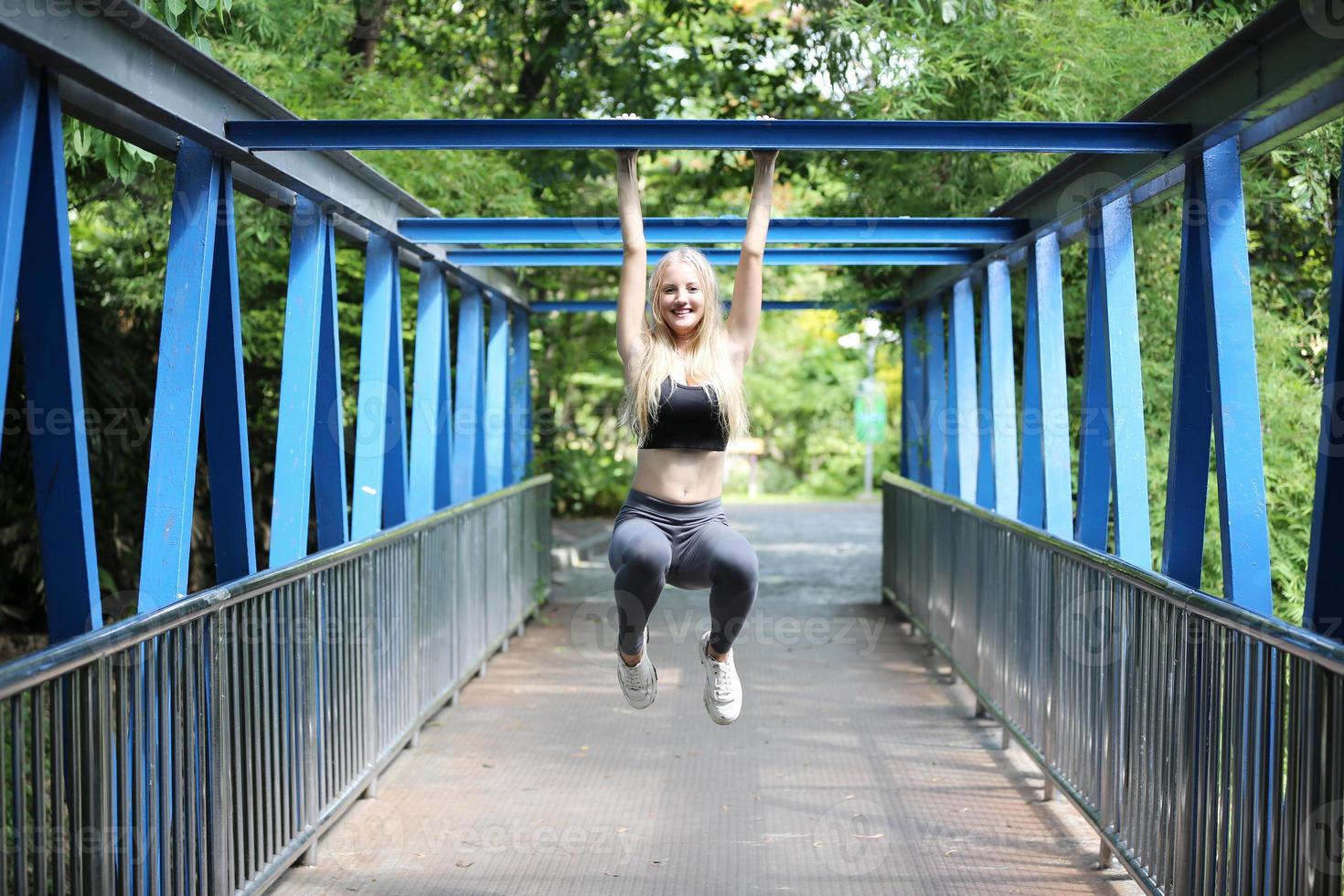 A beautiful woman wearing exercise clothes is playing and enjoying the nature in the garden during the day. photo