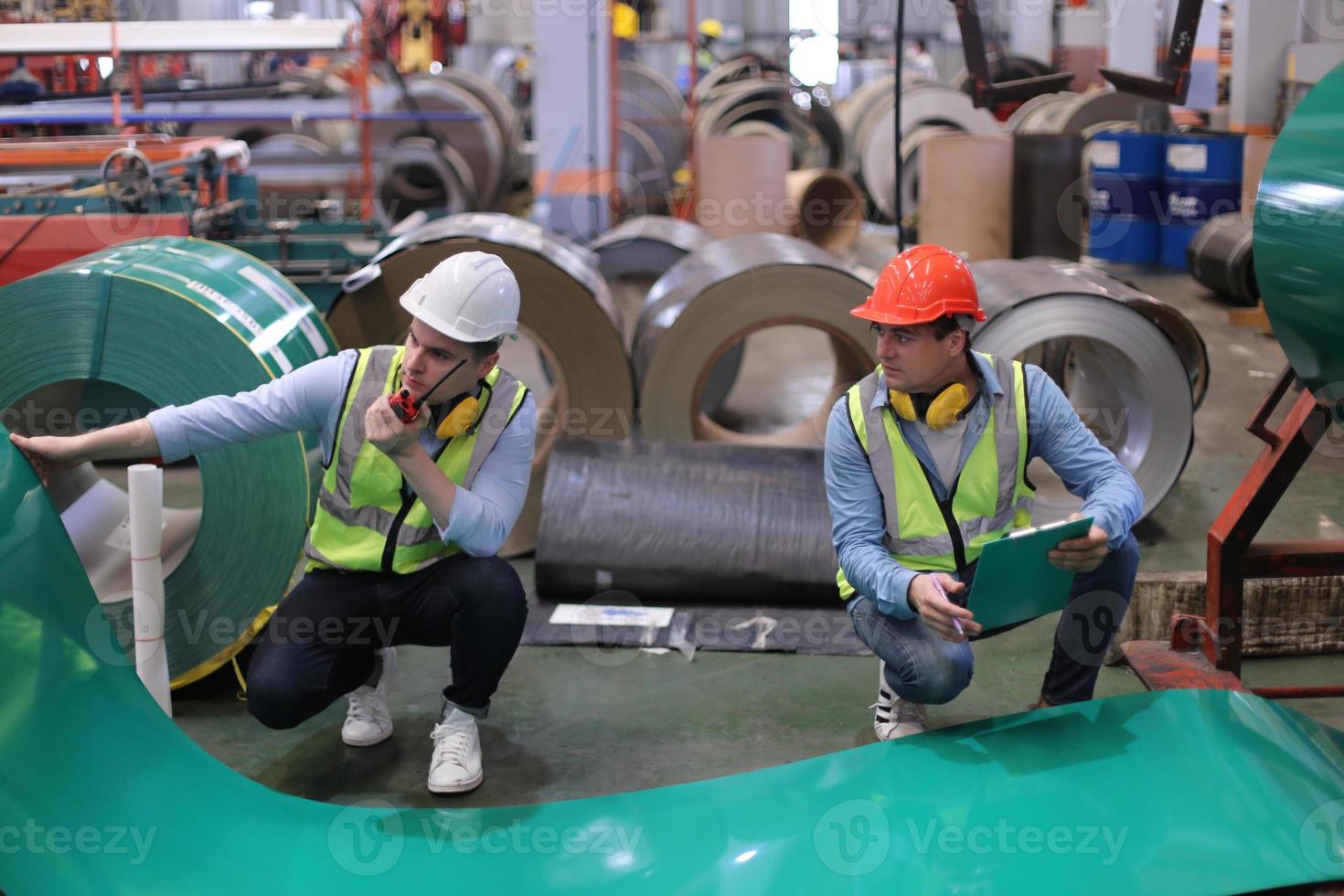 Men industrial engineer wearing a safety helmet while standing in a heavy industrial factory. The Maintenance looking of working at industrial machinery and check security system setup in factory. photo