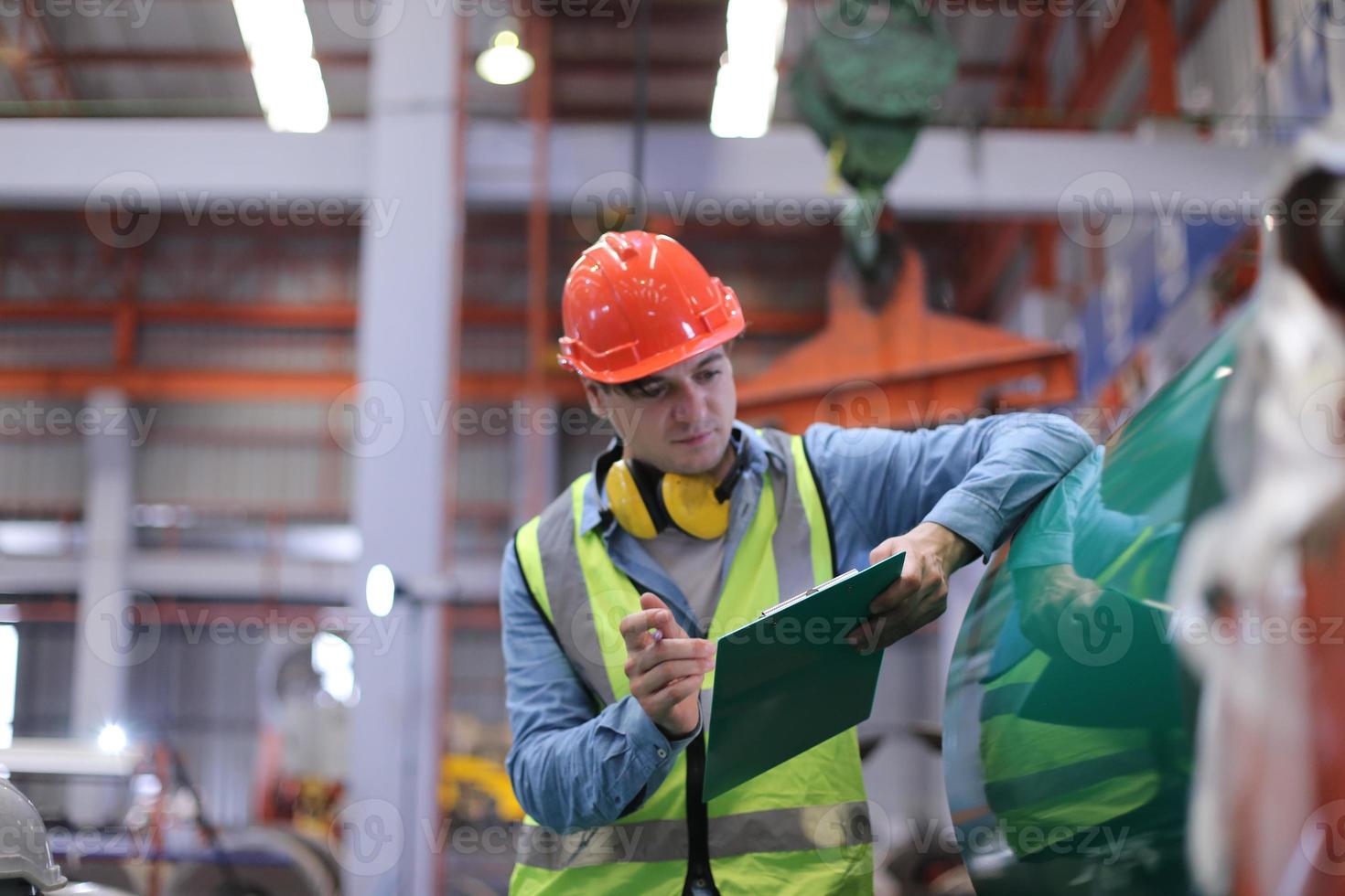 ingeniero industrial masculino con casco de seguridad mientras está de pie en una fábrica industrial pesada. el mantenimiento que busca trabajar en maquinaria industrial y verificar la configuración del sistema de seguridad en fábrica. foto