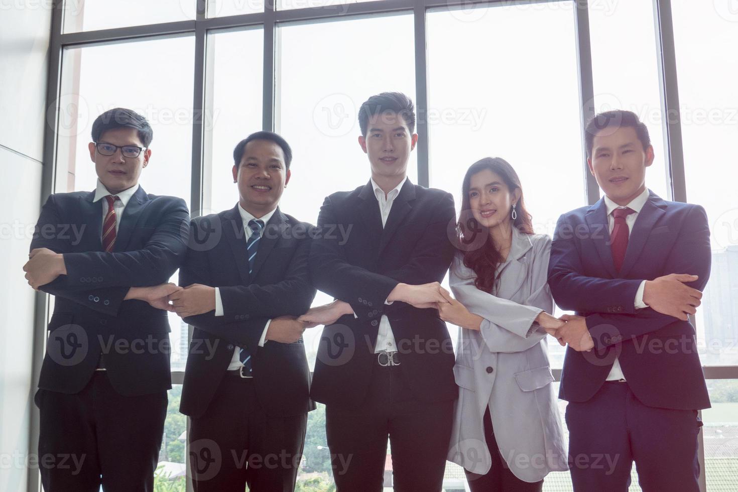 los empresarios exitosos que se unen se ensanchan mostrando una fuerte relación de comunidad de trabajadores. un equipo de hombres de negocios y mujeres de negocios que expresan un sólido trabajo en equipo en la oficina moderna. foto