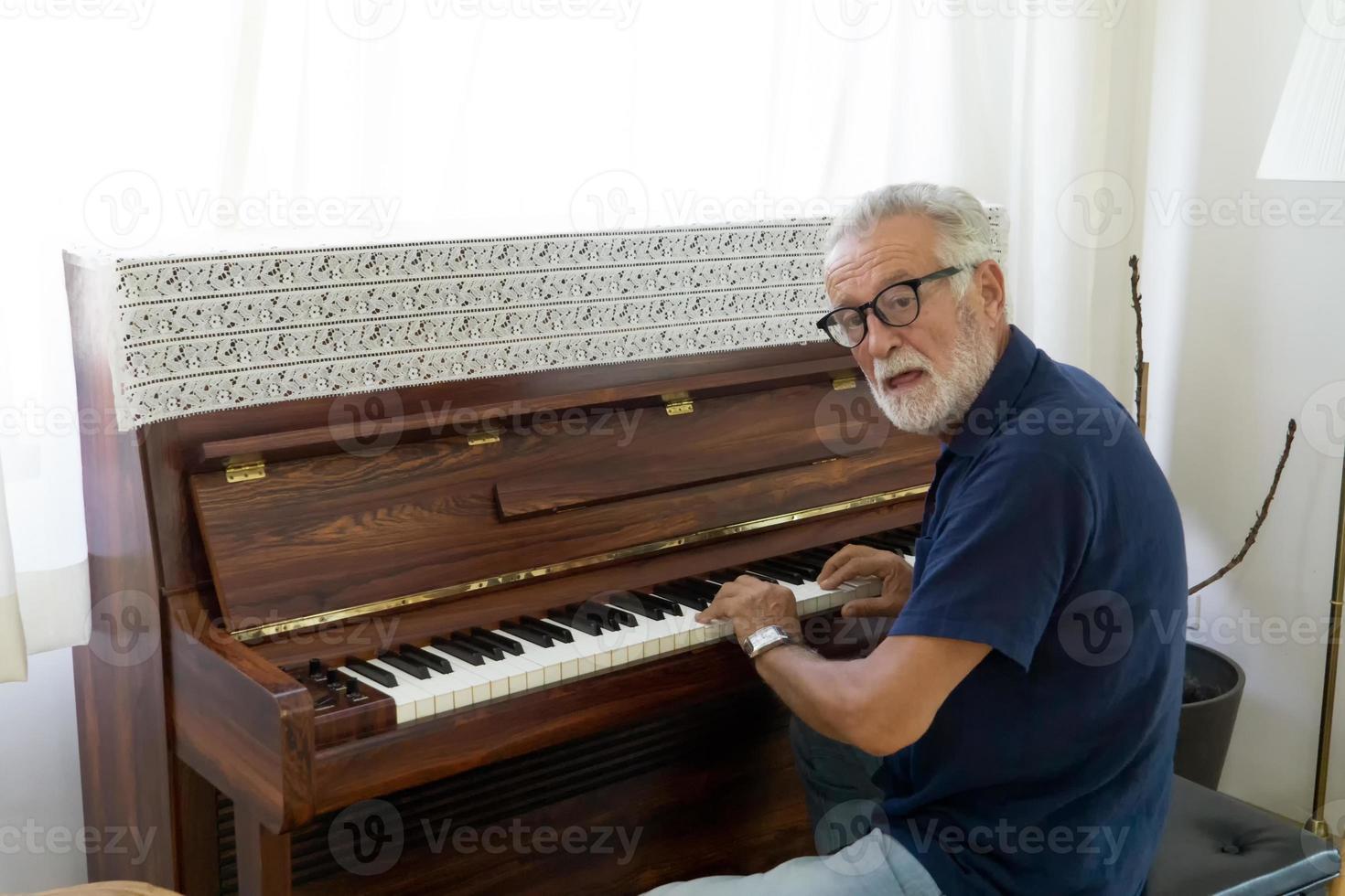 Retired elderly man with gray hair are playing piano on daytime for relaxing photo