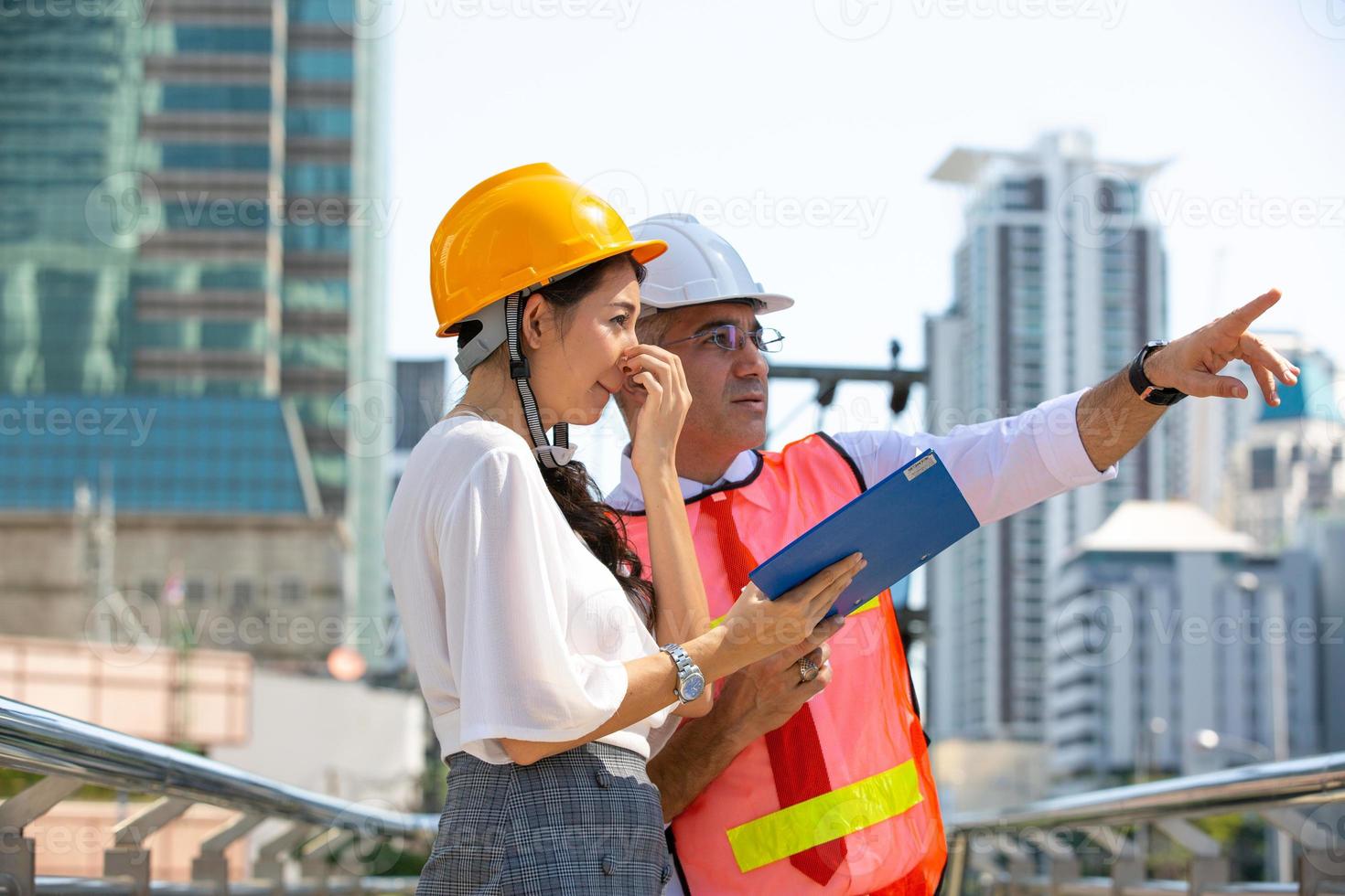 el ingeniero y la mujer de negocios revisando el portapapeles en el edificio del sitio de construcción. el concepto de ingeniería, construcción, vida urbana y futuro. foto