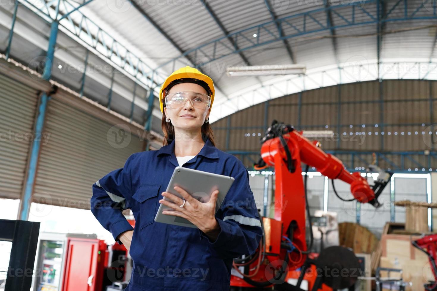 Professional young industrial factory woman employee working with machine part, checking and testing industrial equipment and robot arms in large Electric electronics wire and manufacturing plant photo