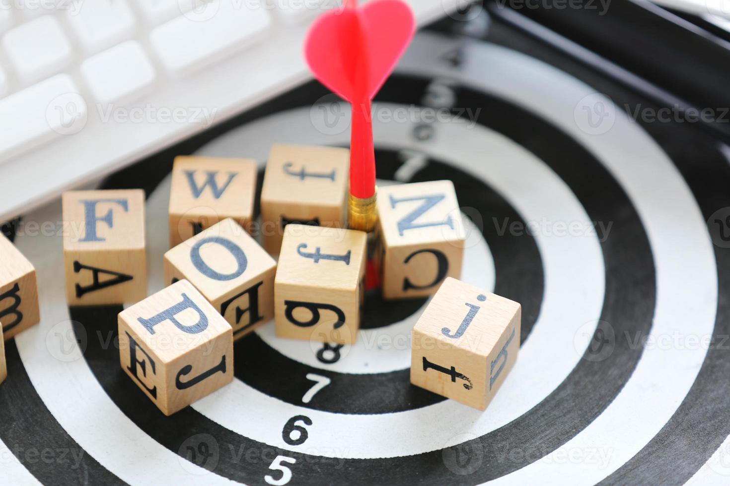 wooden cube with alphabet on target board and white keyboard photo