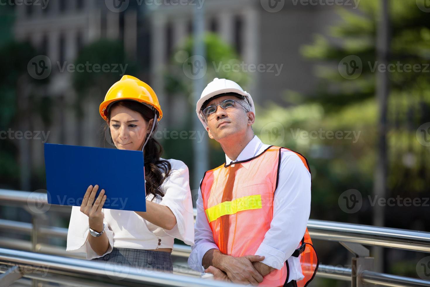 The engineer and business woman checking on clipboard at construction site building. The concept of engineering, construction, city life and future. photo