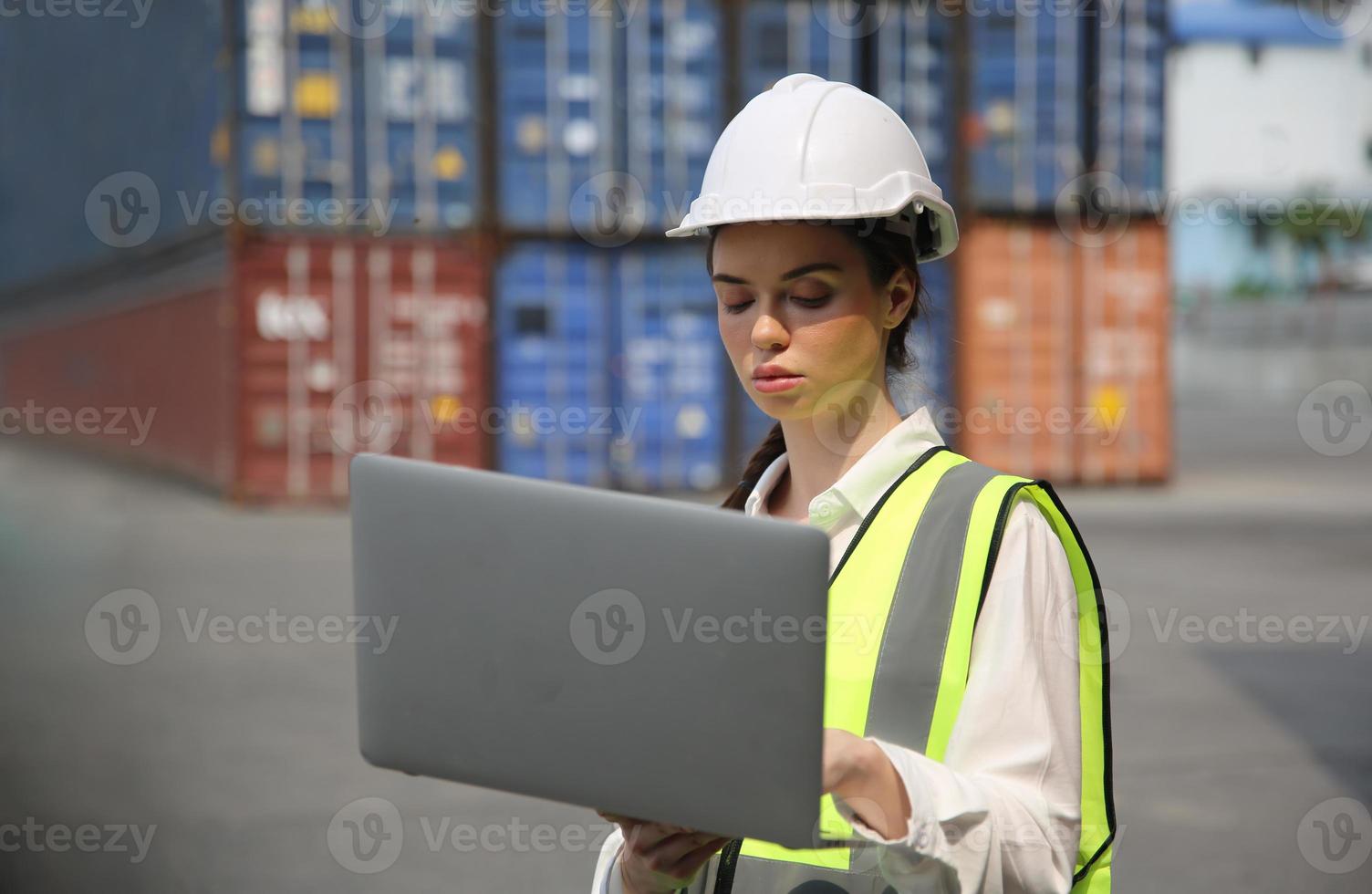 mujer hermosa joven que usa una computadora portátil en el puerto de la terminal de contenedores. foto