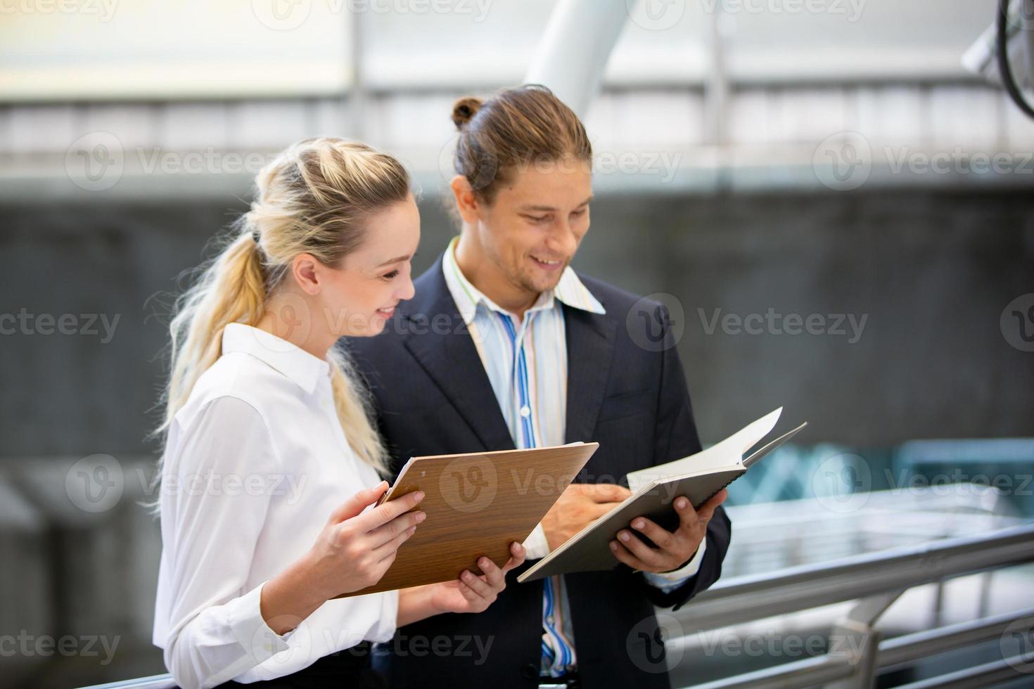 Two business people discussing on project while walking at outside. photo