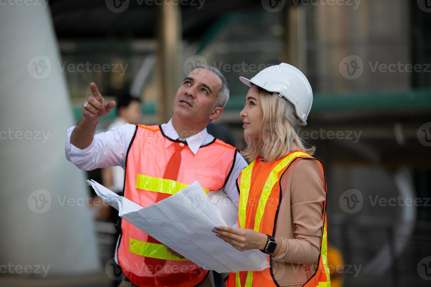 Contractor and architect looking at plan and talking about working on big project. Building in construction process interior. photo