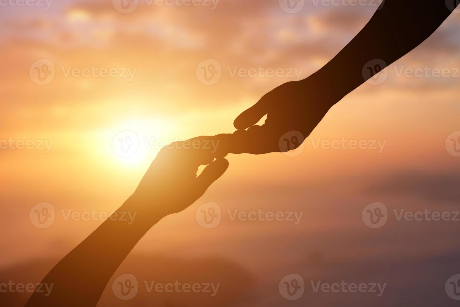 Silhouette of giving a helping hand, hope and support each other over sunset background. photo