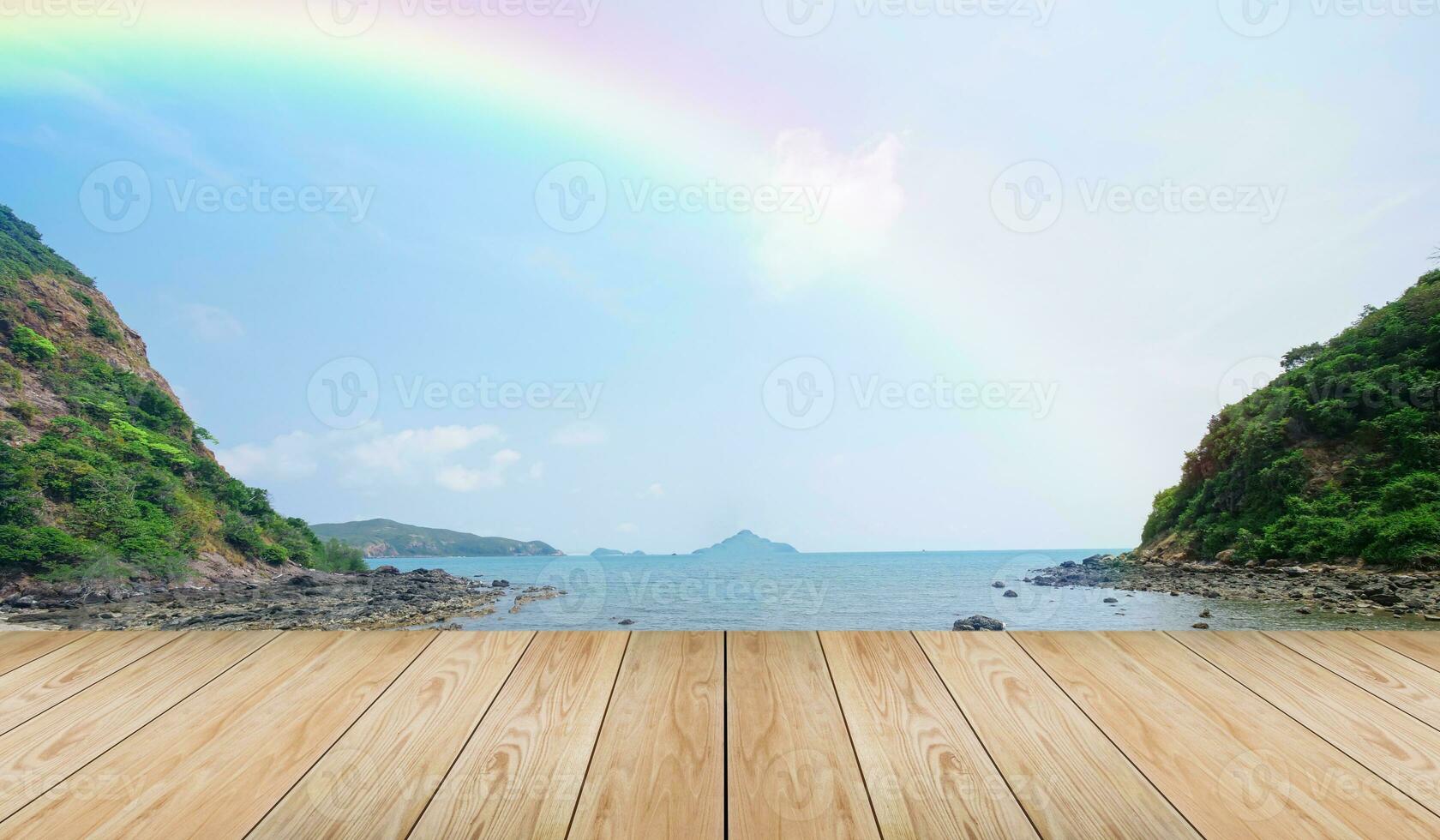 Empty wooden tabletop and view tropical beach with raibow over sea background photo