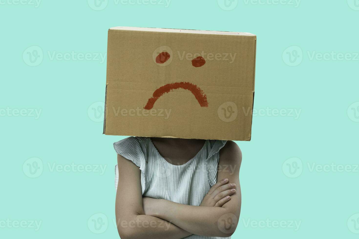 Little girl wearing cardboard box on his head with unglucklich, Isolated on blue background. photo