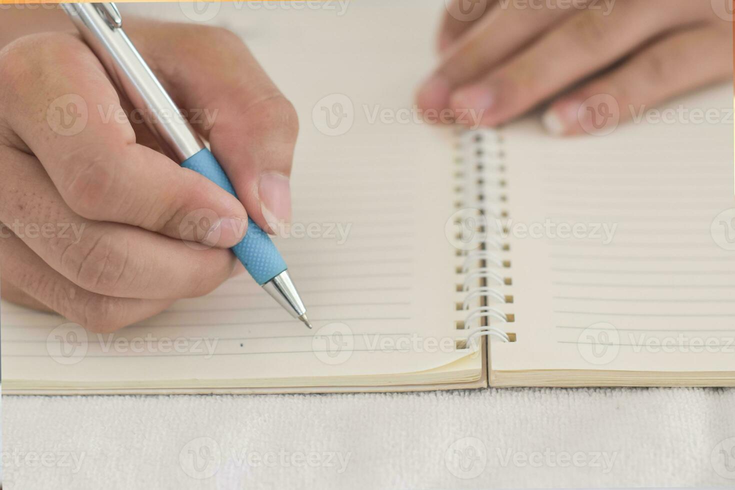 primer plano de la mano masculina con pluma escribiendo en un cuaderno. foto