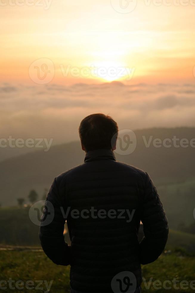 man watching sunrise at hilltop photo