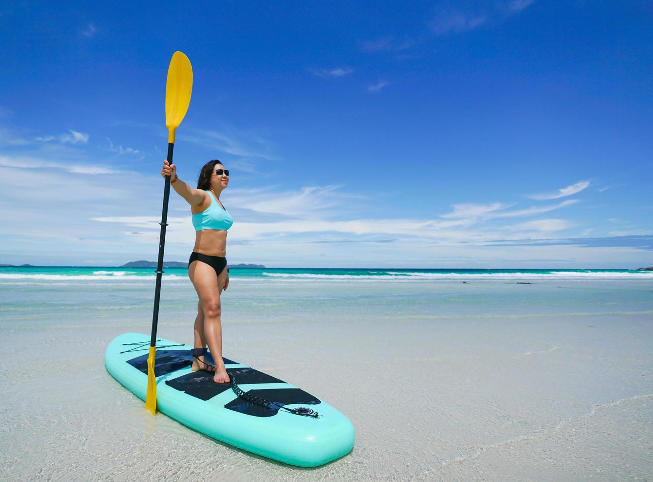 mujer a bordo de sup en la playa foto