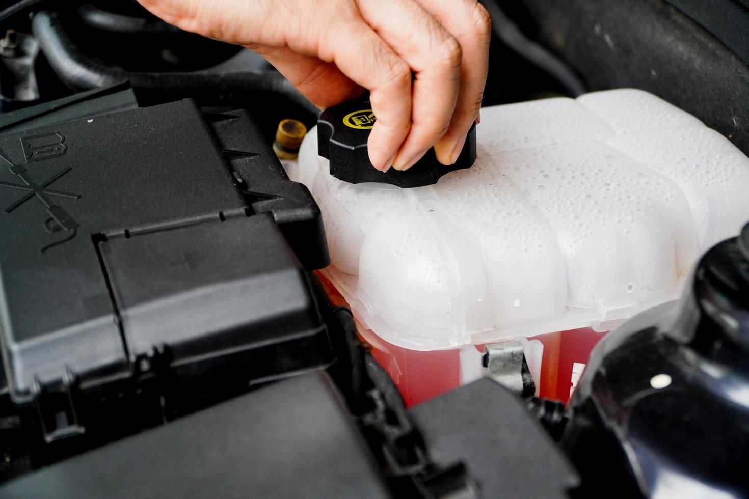 mechanic inspects the expansion tank with pink antifreeze. Vehicle coolant level in the car's radiator system. auto parts photo