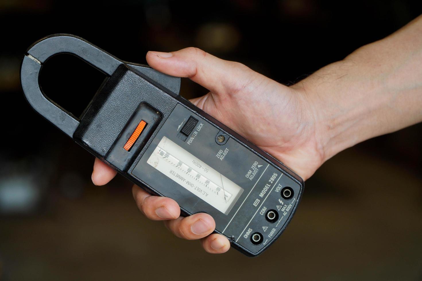 Male hand holding an analog clamp meter,concept of electric current photo