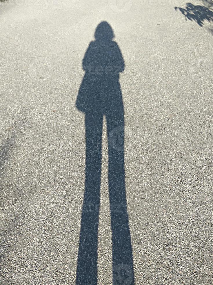 Shadow of a tall girl on an asphalt road. photo