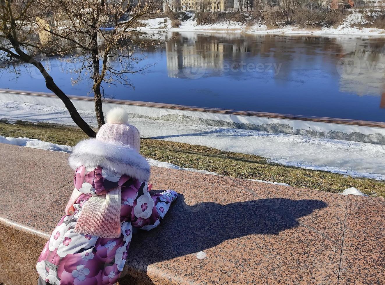 una niña pequeña mira el río después de la deriva del hielo primaveral. foto