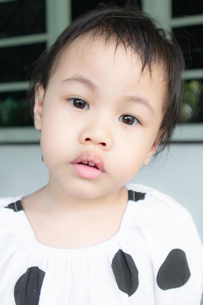 3 years old cute baby Asian girl looking at camera with absent minded face. photo