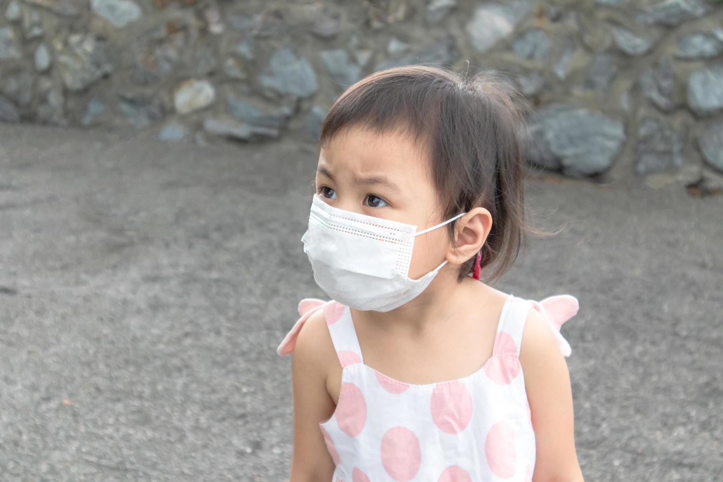 3 years old Asian girl wearing white protective face mask during coronavirus COVID-19. photo