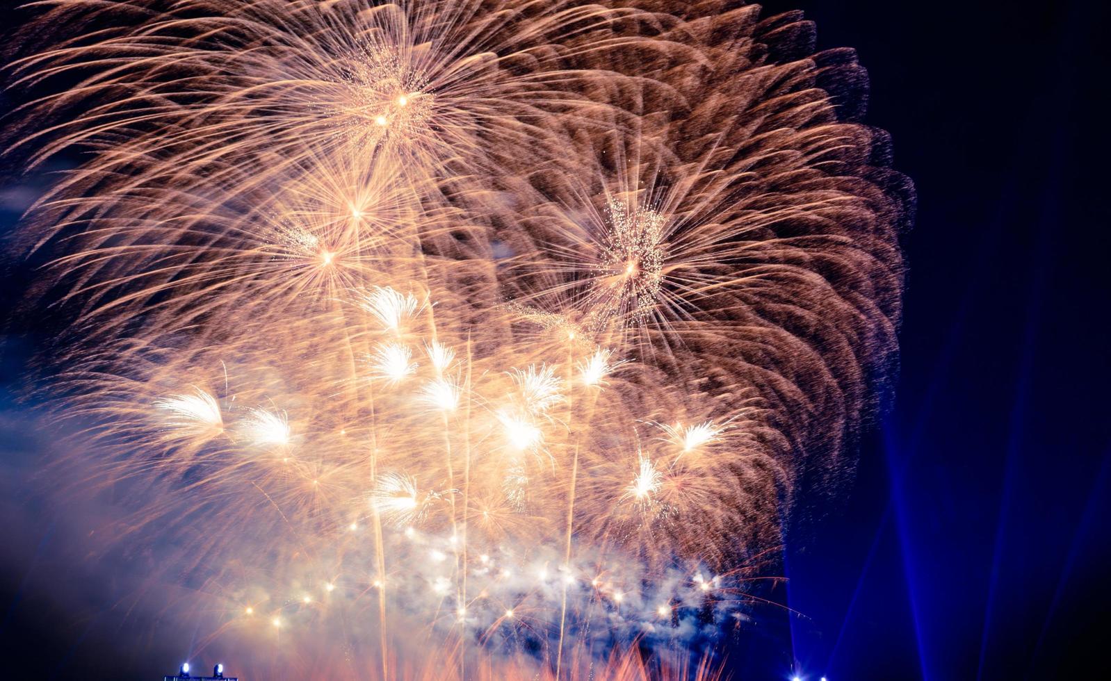 multitud viendo fuegos artificiales y celebrando la fundación de la ciudad. hermoso y colorido espectáculo de fuegos artificiales en la ciudad para celebrar en el fondo oscuro de la noche. foto