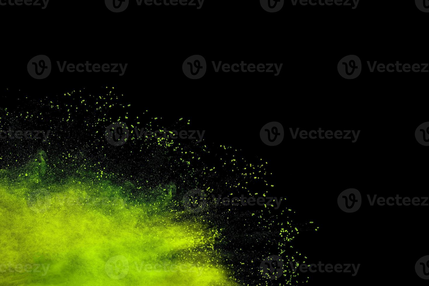 Abstract green dust splattered on black background. Freeze motion of green powder splash. photo