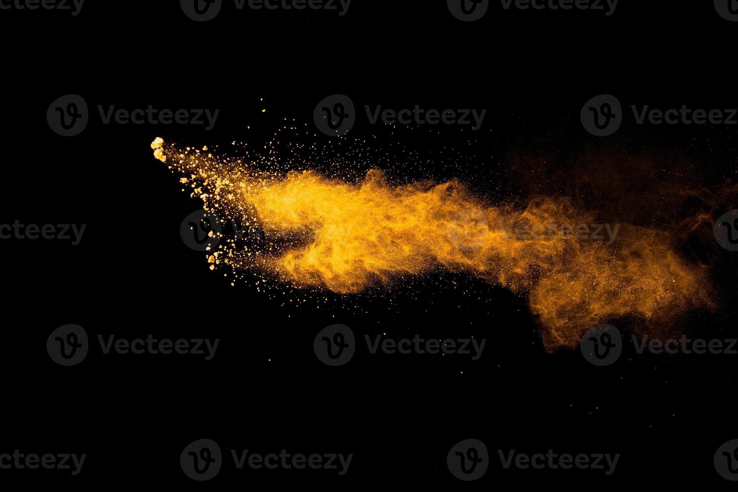 Abstract explosion of orange dust on black background.Freeze motion of orange powder burst. photo