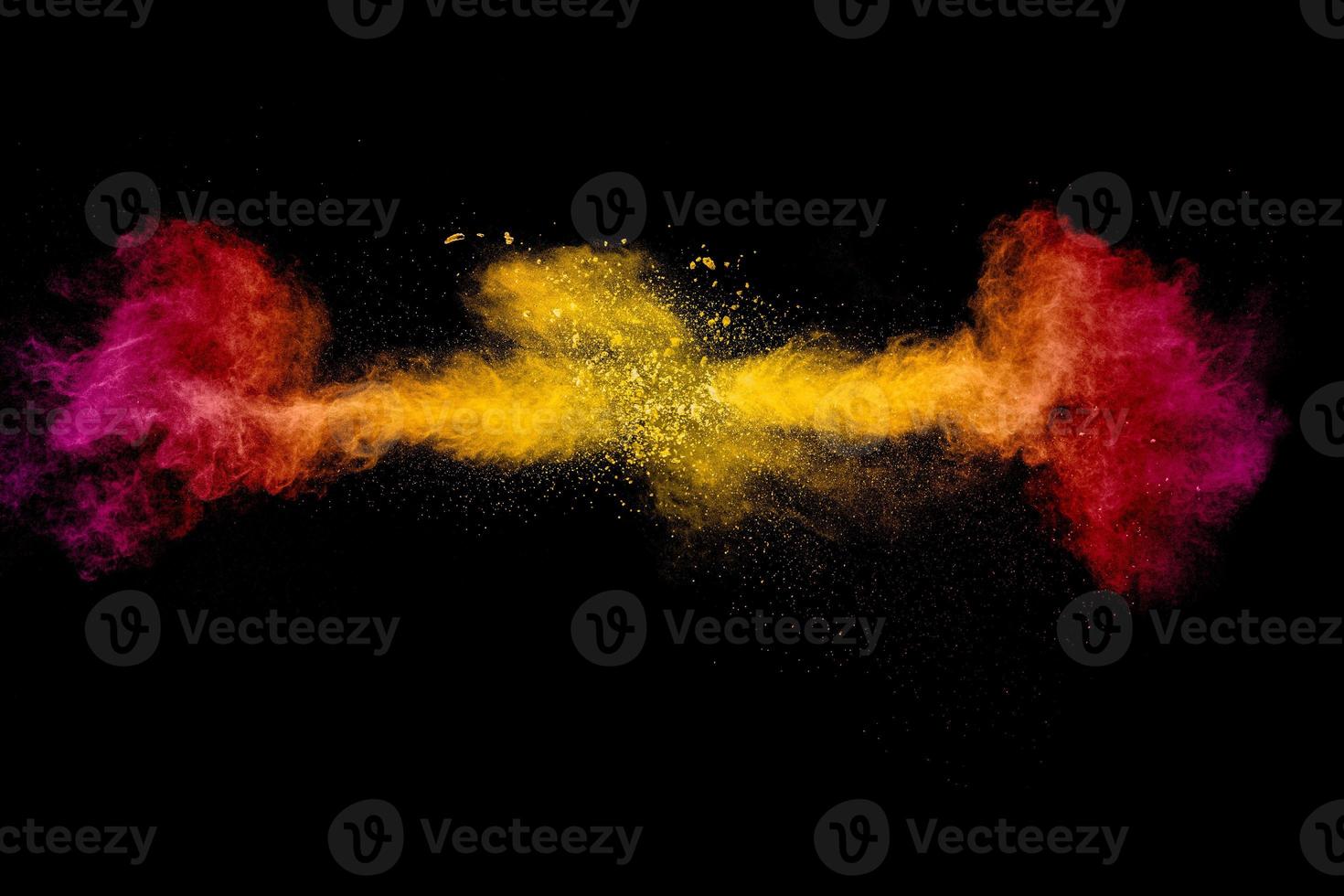 Abstract explosion of orange pink dust on black background.Freeze motion of orange pink powder burst. photo