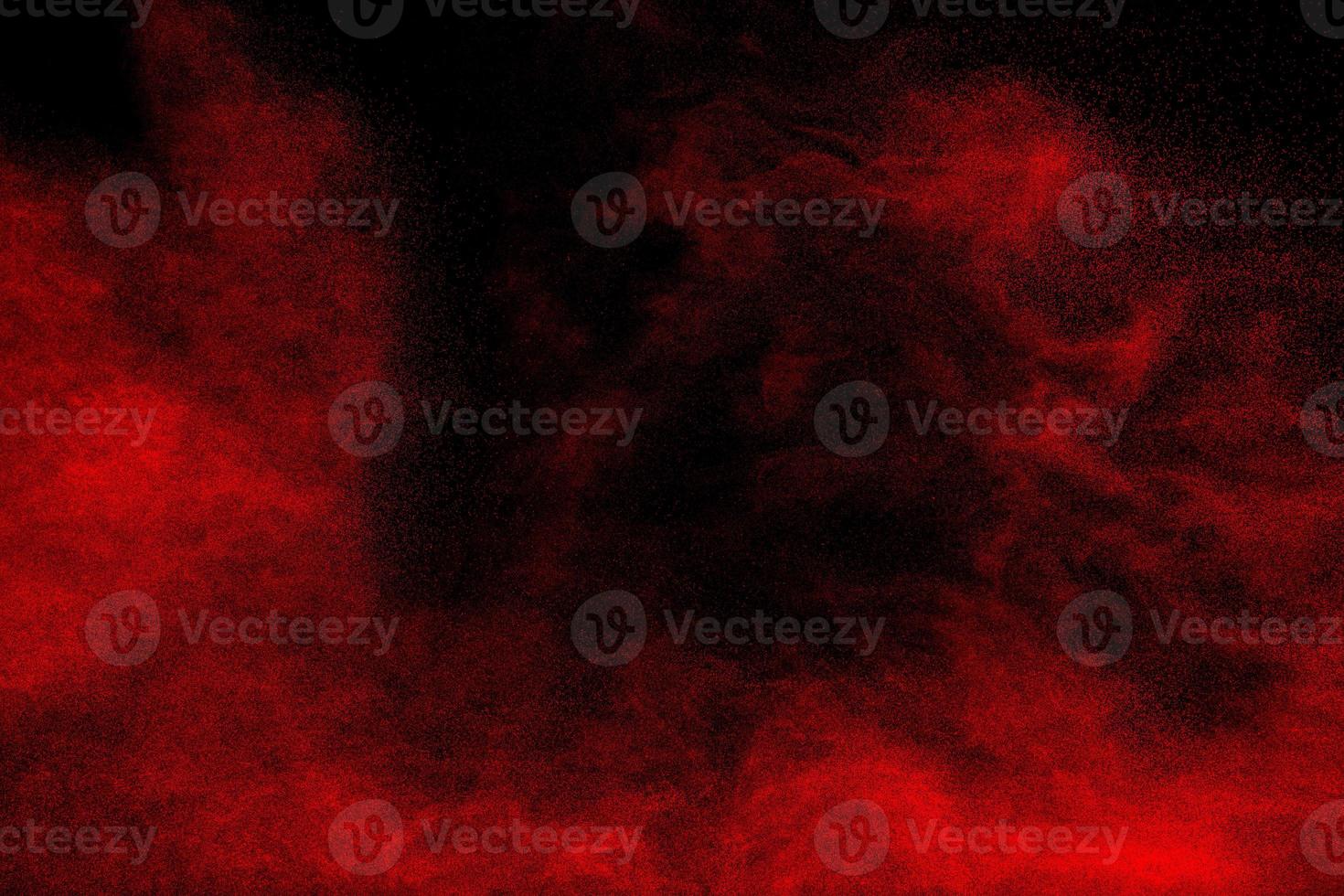 Red powder explosion cloud on black background. Freeze motion of red color dust  particles splashing. photo