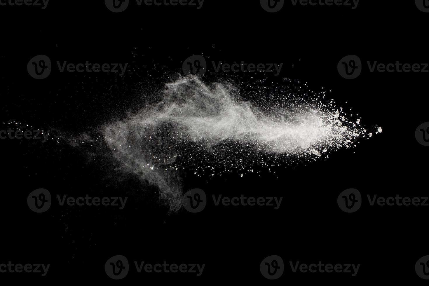 White powder explosion isolated on black background.White dust particles splash. photo