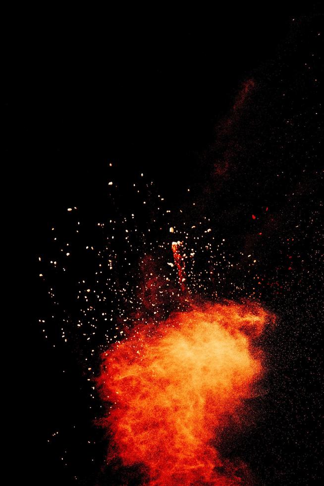 Red orange color powder explosion cloud isolated on black background. photo