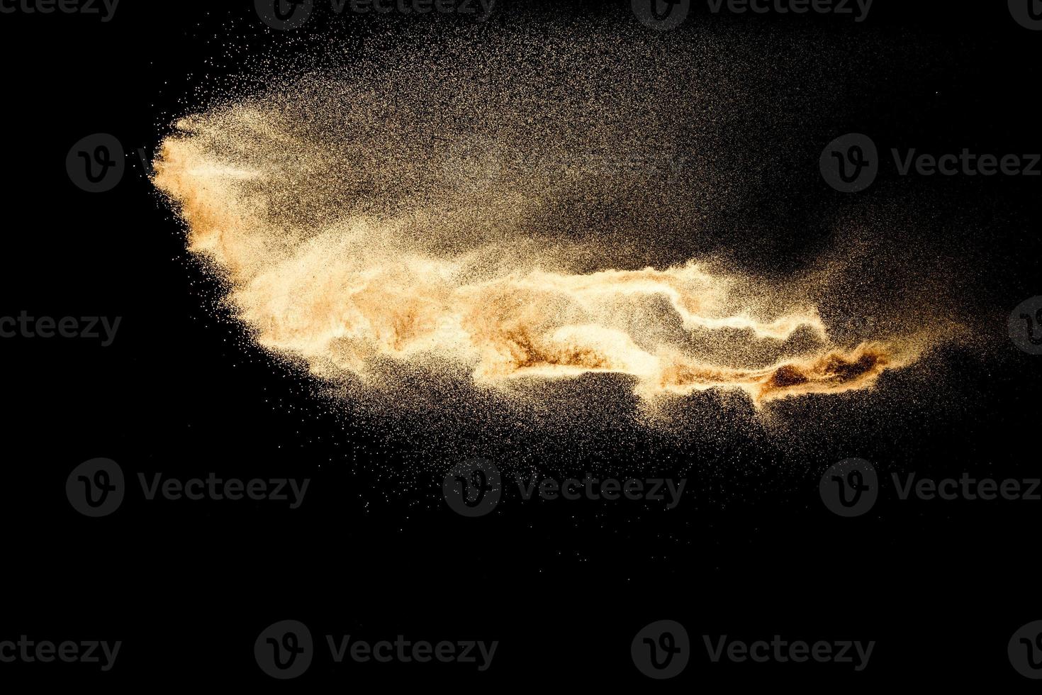 Abstract sand cloud.Golden colored sand splash agianst dark background.Yellow sand fly wave in the air. Sand explode on black background ,throwing freeze stop motion concept. photo
