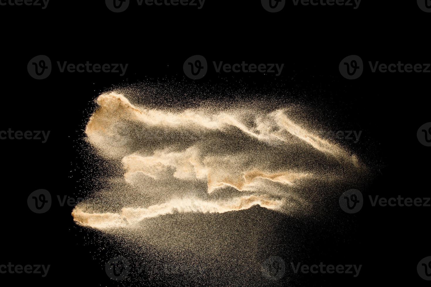 Abstract sand cloud.Golden colored sand splash agianst dark background.Yellow sand fly wave in the air. Sand explode on black background ,throwing freeze stop motion concept. photo