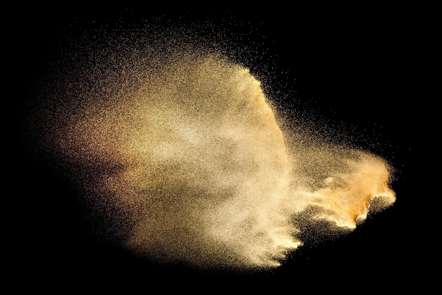 Sand explosion isolated on black background. Freeze motion of sandy dust splash. photo