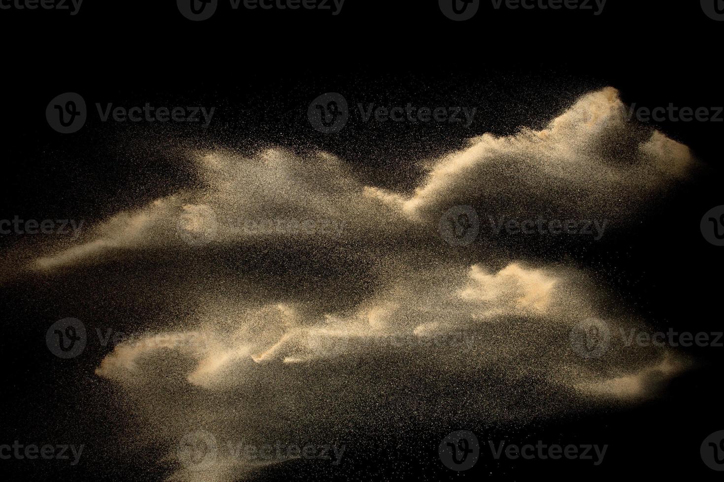 Sand explosion isolated on black background. Freeze motion of sandy dust splash. photo