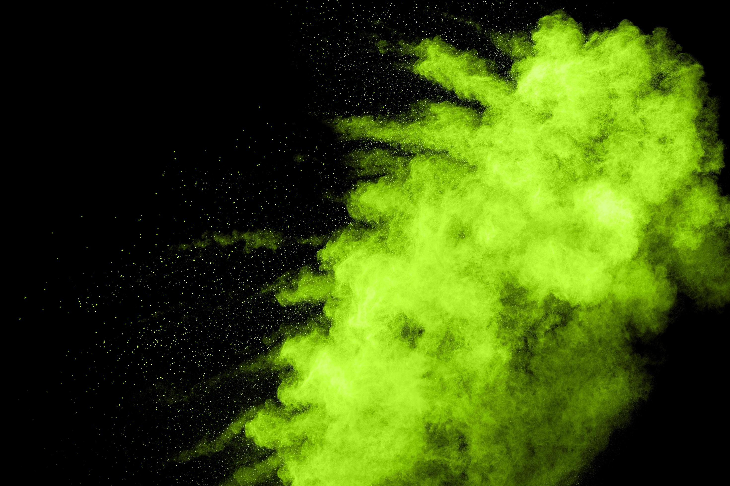 Green color powder explosion cloud on black background.Green dust