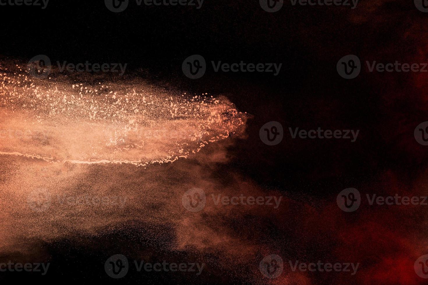 lanzar partículas marrones explotando sobre fondo negro. salpicaduras de polvo marrón. foto